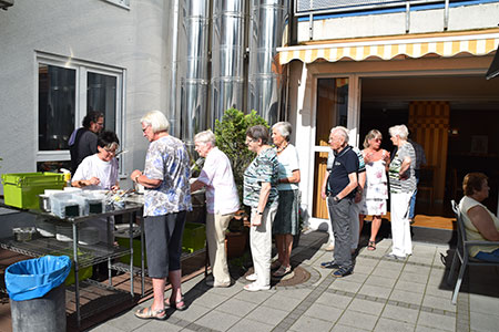 Bild zeigt die Bewohner der Seniorenanlage in Haan bei einem Grillfest im Garten